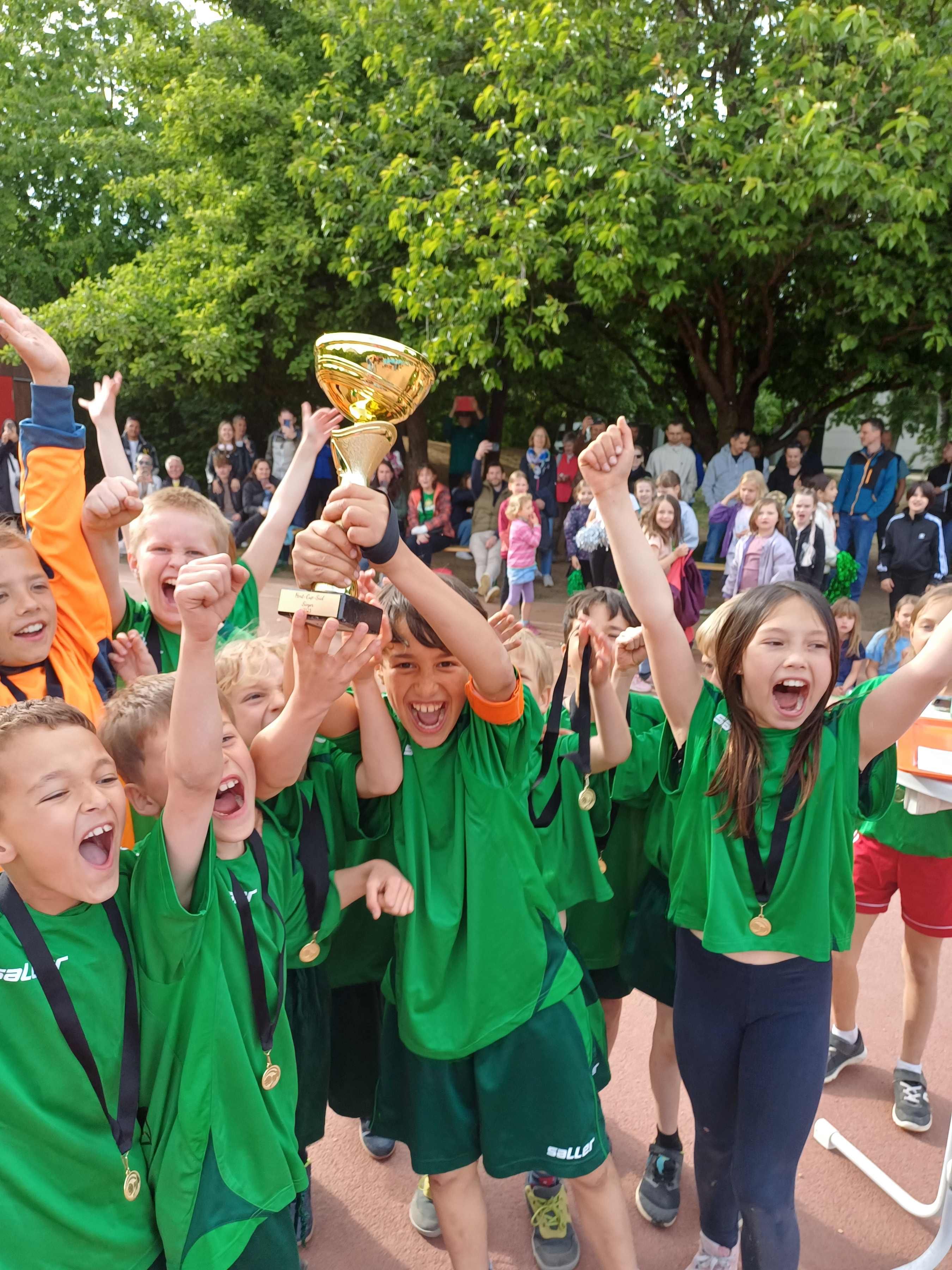 Fotografie – Die Gewinnerkinder jubeln mit ihrem Pokal