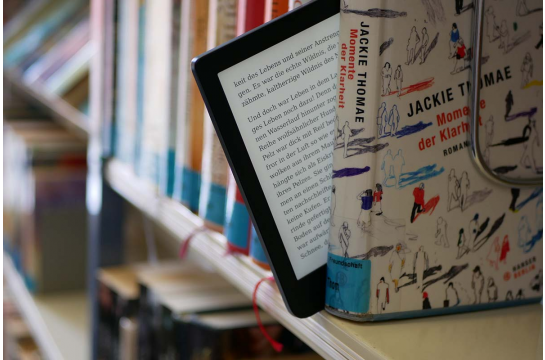 E-Bookreader, der aus einer Reihe Papierbücher herausragt