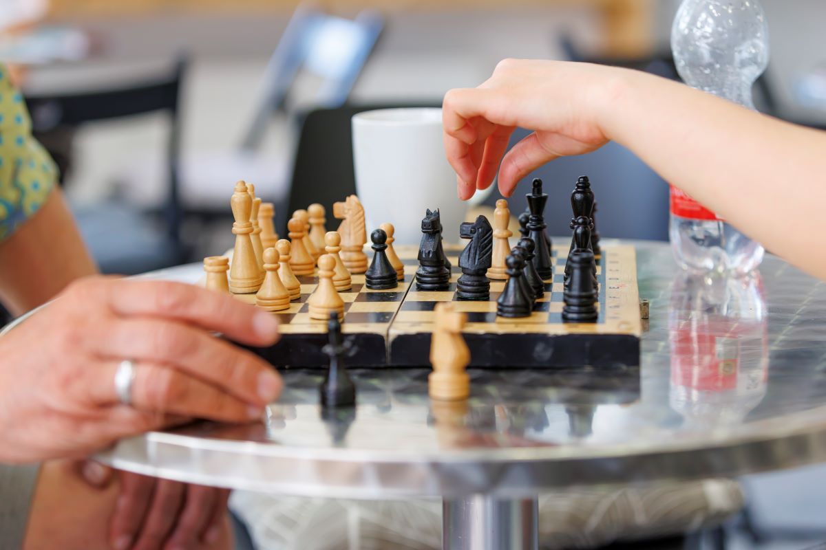 Fotografie: Schachbrett mit zwei schachspielenden Händen, aufgenommen im M26