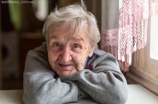 Themenbild Städtische Stiftungen Altenhilfe - Symbolbild - Seniorin mit verschränkten Armen am Tisch