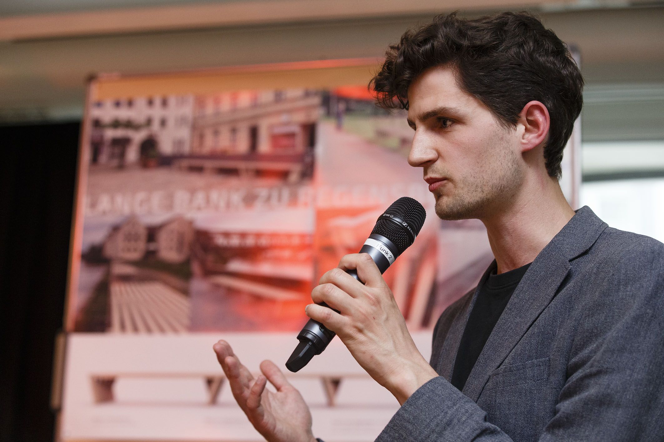 Aktion Sondermöbel - Foto einer Veranstaltung - vor einer Infowand am Mikrofon Johannes von Schoenebeck