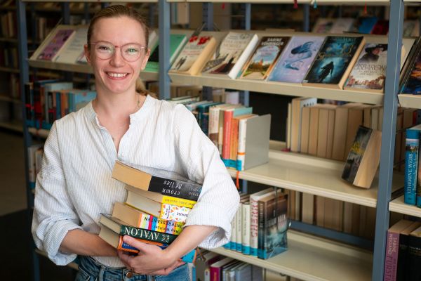 Fotografie: Eine Frau hält einen Stapel Bücher in der Hand.