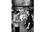 Fotografie – schwarz/weiß Bild mit Menschen in einer Fußgängerzone unter einem Barschild