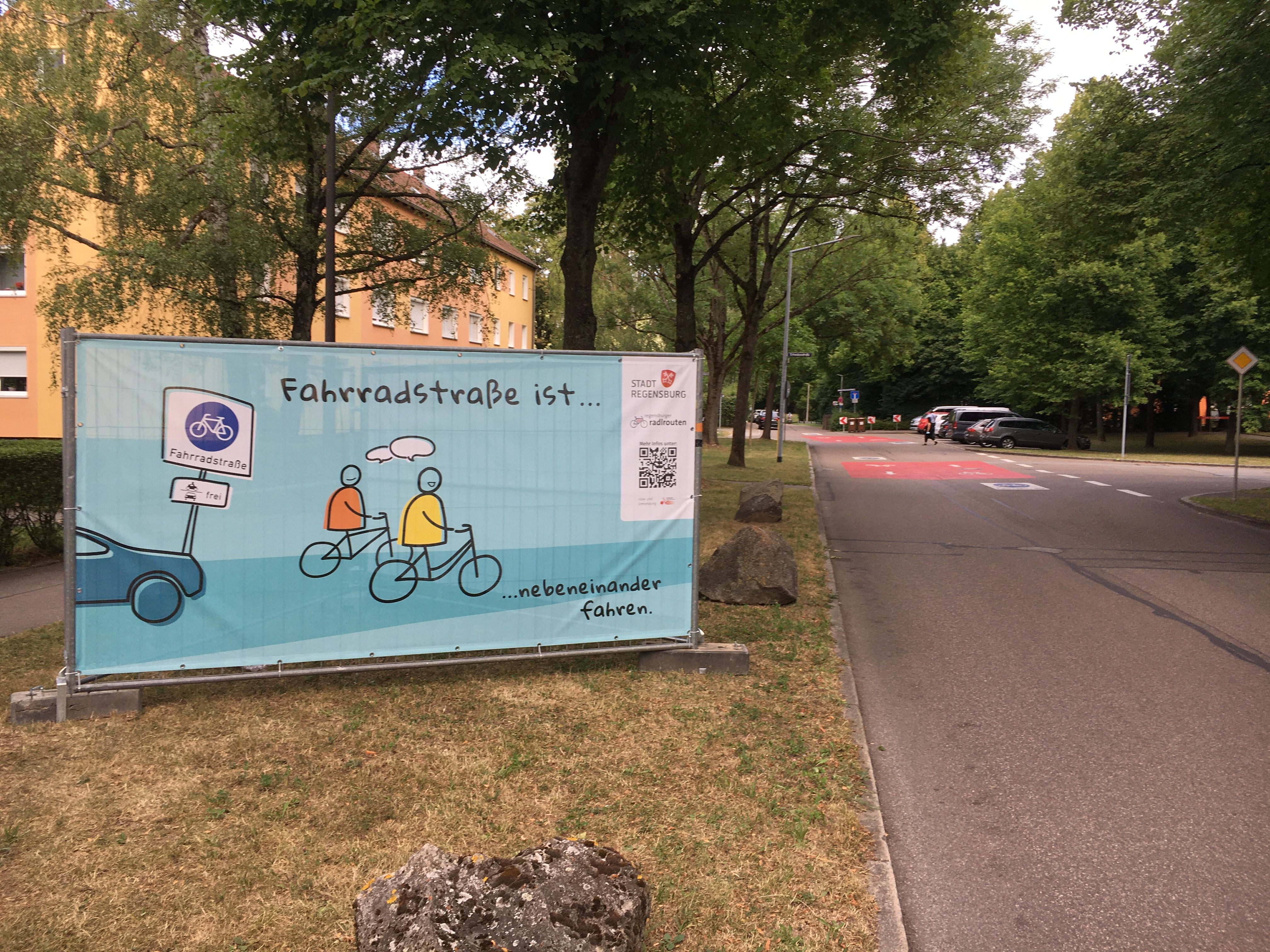 Fotografie eines blauen Banners mit dem Spruch "Fahrradstraße ist... nebeneinander fahren."