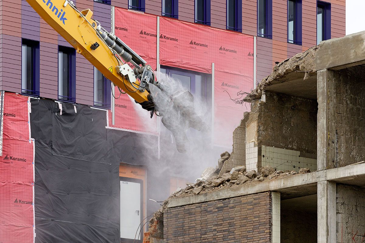Fotografie - Nahaufnahme vom Bagger, der die Fassade abbricht