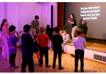 Kinder stehen in der erleuchteten Kinderdisco und singen Karaoke mit Mikrofonen (C) Stadt Regensburg, Amt für kommunale Jugendarbeit