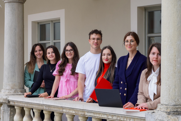 Fotografie - Gruppe junger Menschen steht an einer Balustrade eines Gebäudes.
