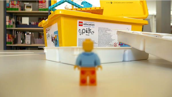 Legomännchen vor einer großen Kiste mit Legosteinen.