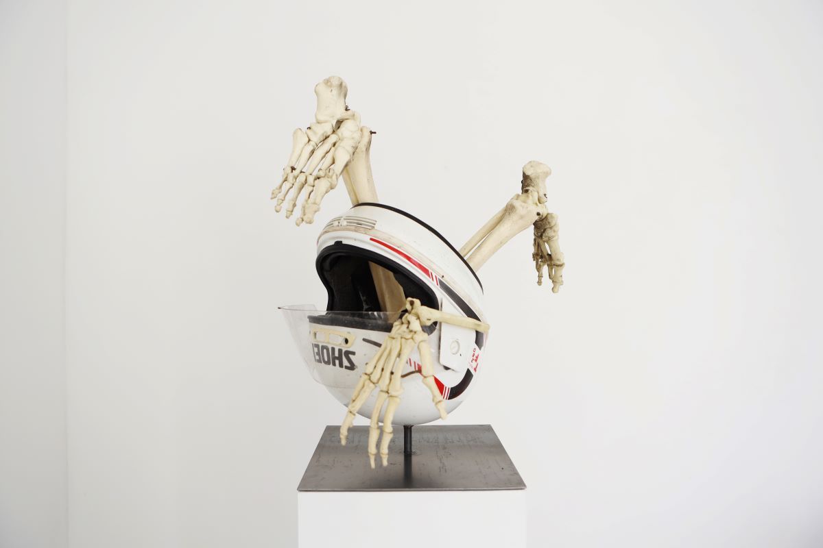 Kunstwerk: Motorradhelm aufgehängt auf Skelettknochen