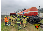 Einsatzkräfte in Schutzkleidung stehen vor dem Kesselwagen