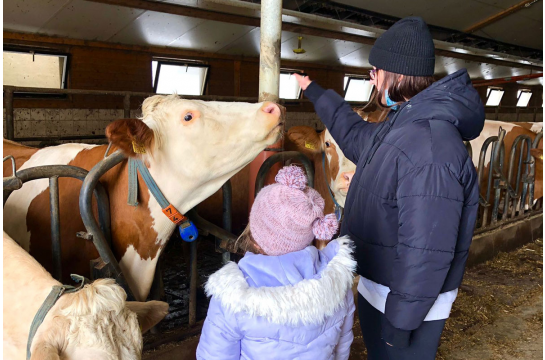 Fotografie: Ein Kind und eine Frau im Kuhstall