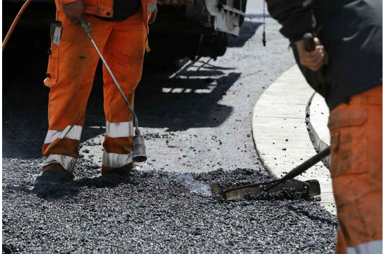 Aktuelle Baustellen - foto zwei Personen beim Aufbringen eines neuen Straßenbelags