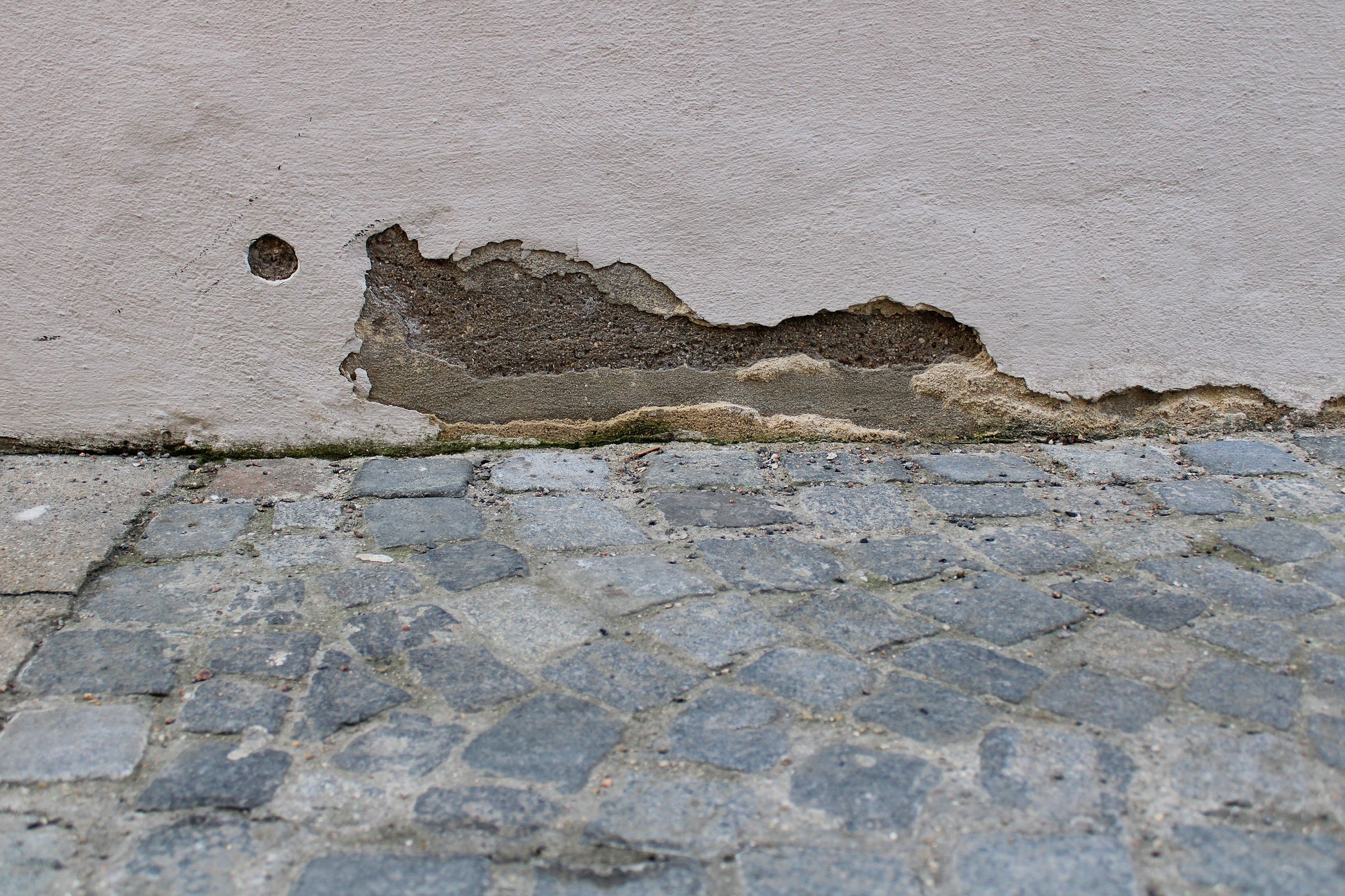 Fotografie – Blick auf eine Hauswand an welcher der Putz abbröckelt