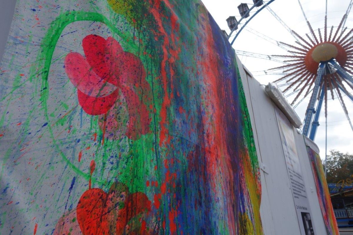 Fotografie - bunt bemalte Holzwände mit Riesenrad im Hintergrund