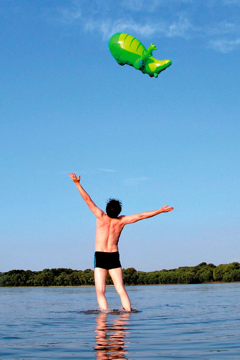 Kulturplattform Donauraum - Mann steht in der Donau - in der Luft ein grüner Drachen-Luftballon 