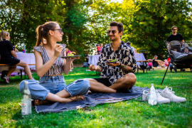 Fotografie: Ein Mann und eine Frau sitzen auf einer Picknickdecke und essen.