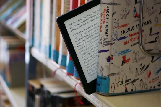E-Bookreader, der aus einer Reihe Papierbücher herausragt (C) Johanna Sippel