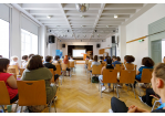 Fotografie - Internationale Jugendkonferenz 2022 - Blick in einen Konferenzraum anlässlich der Eröffnung der Jugendkonferenz; im Hintergrund Oberbürgermeisterin Gertrud Maltz-Schwarzfischer am Rednerpult