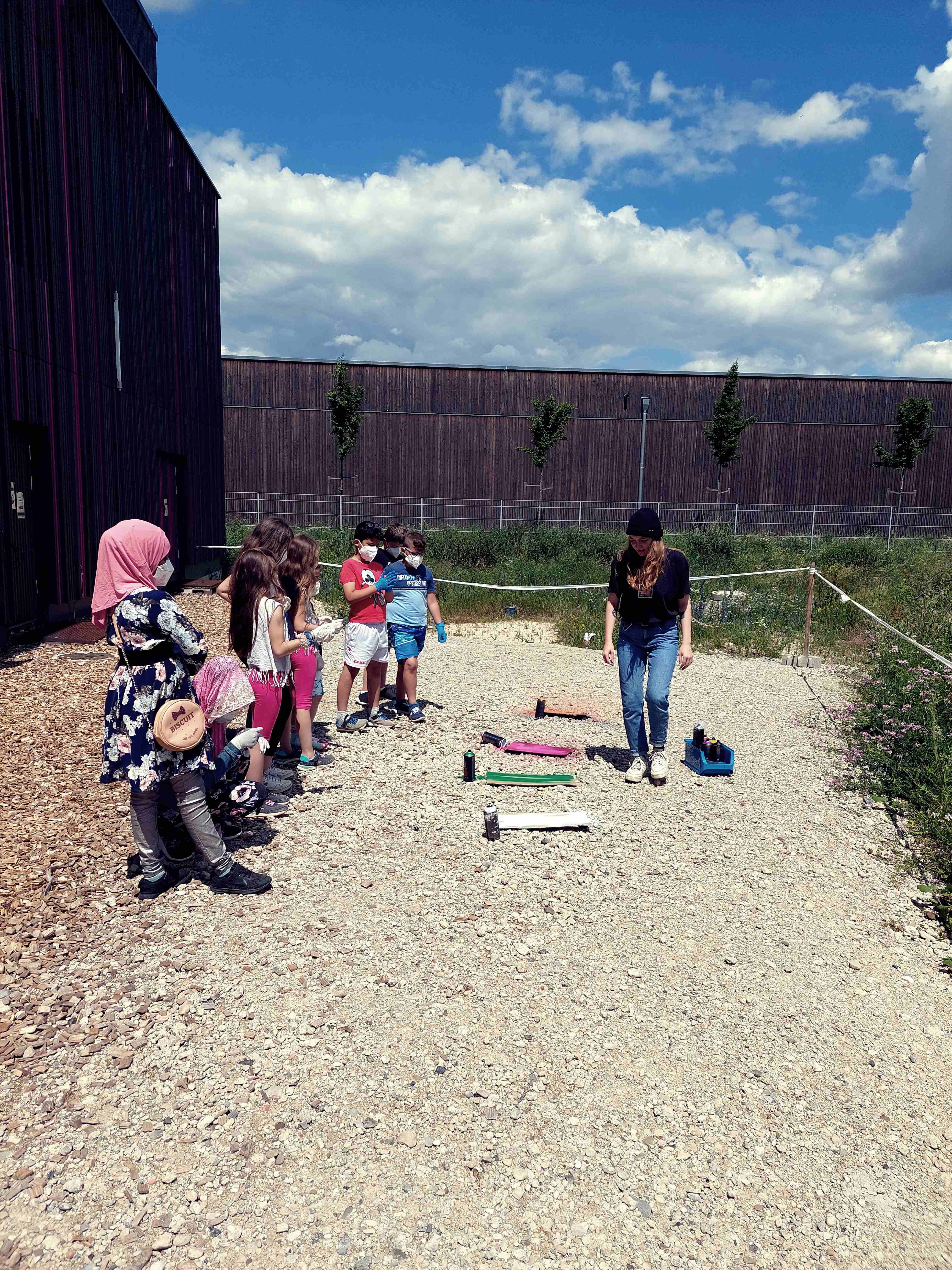 Auf dem Foto sind mehrere Kinder und eine Pädagogin hinter dem Jugendzentrum Guericke zu sehen.