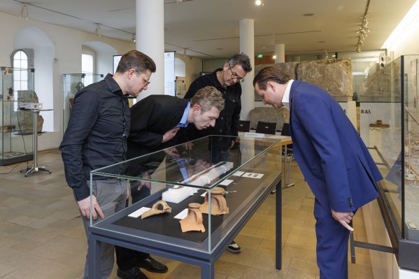 Fotografie: Vier Herren begutachten die Fundstücke beim Pressetermin zum Mithras-Heiligtum.