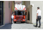 Fotografie: Ein Leiterwagen der Feuerwehr in einer engen Altstadtgassen, zwei Männer geben Anweisungen.