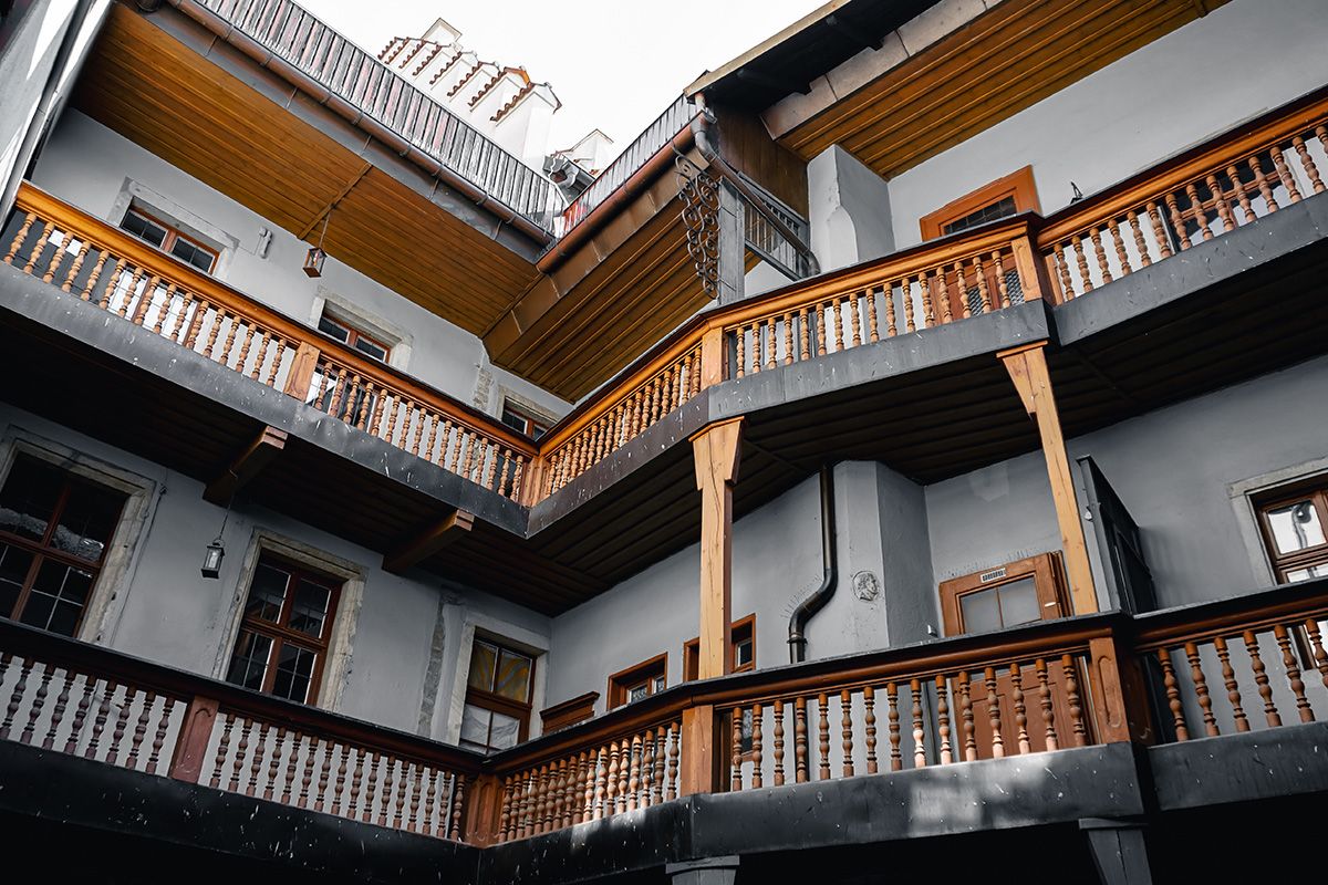 Fotografie - Mehrstöckiger Innenhof eines altertümlichen Gebäudes in Regensburg mit Holzbalkonen und umlaufenden Galerien.