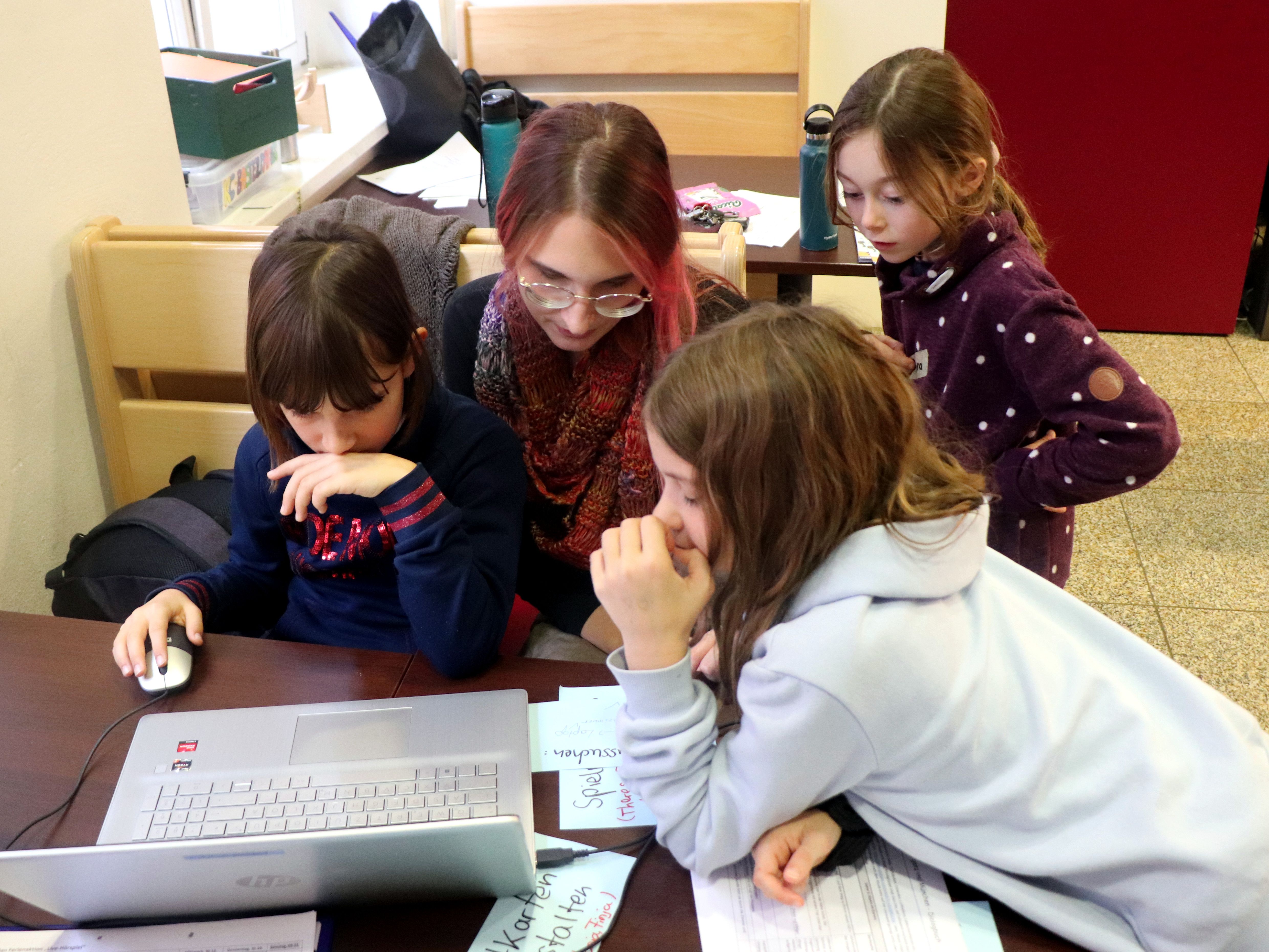 Melissa Voet und drei Kinder schauen in einen Laptop
