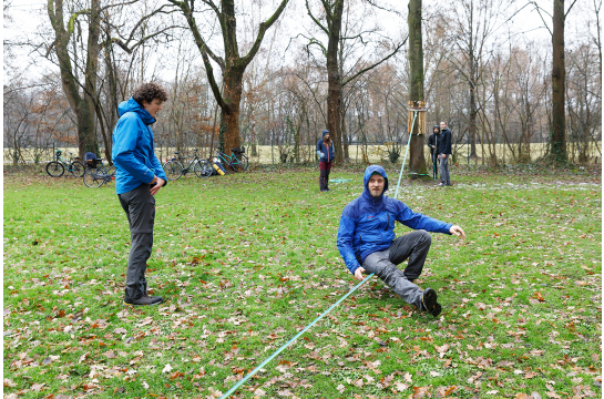 Mann sitzt auf gespannter Slackline