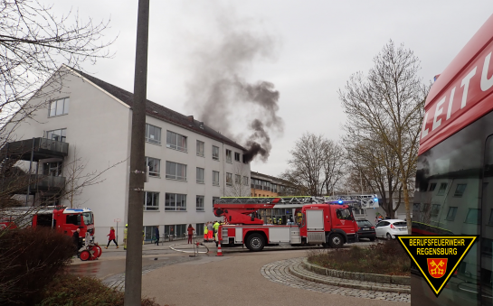Rauch aus Schule mit Feuerwehrfahrzeugen