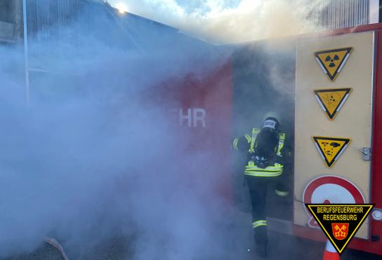 Fotografie: Einsatzkraft der Feuerwehr mit Atemschutzgerät betritt einen verrauchten Container.