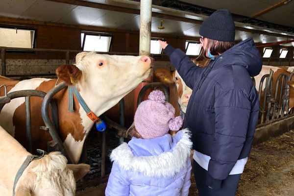 Fotografie: Ein Kind und eine Frau im Kuhstall
