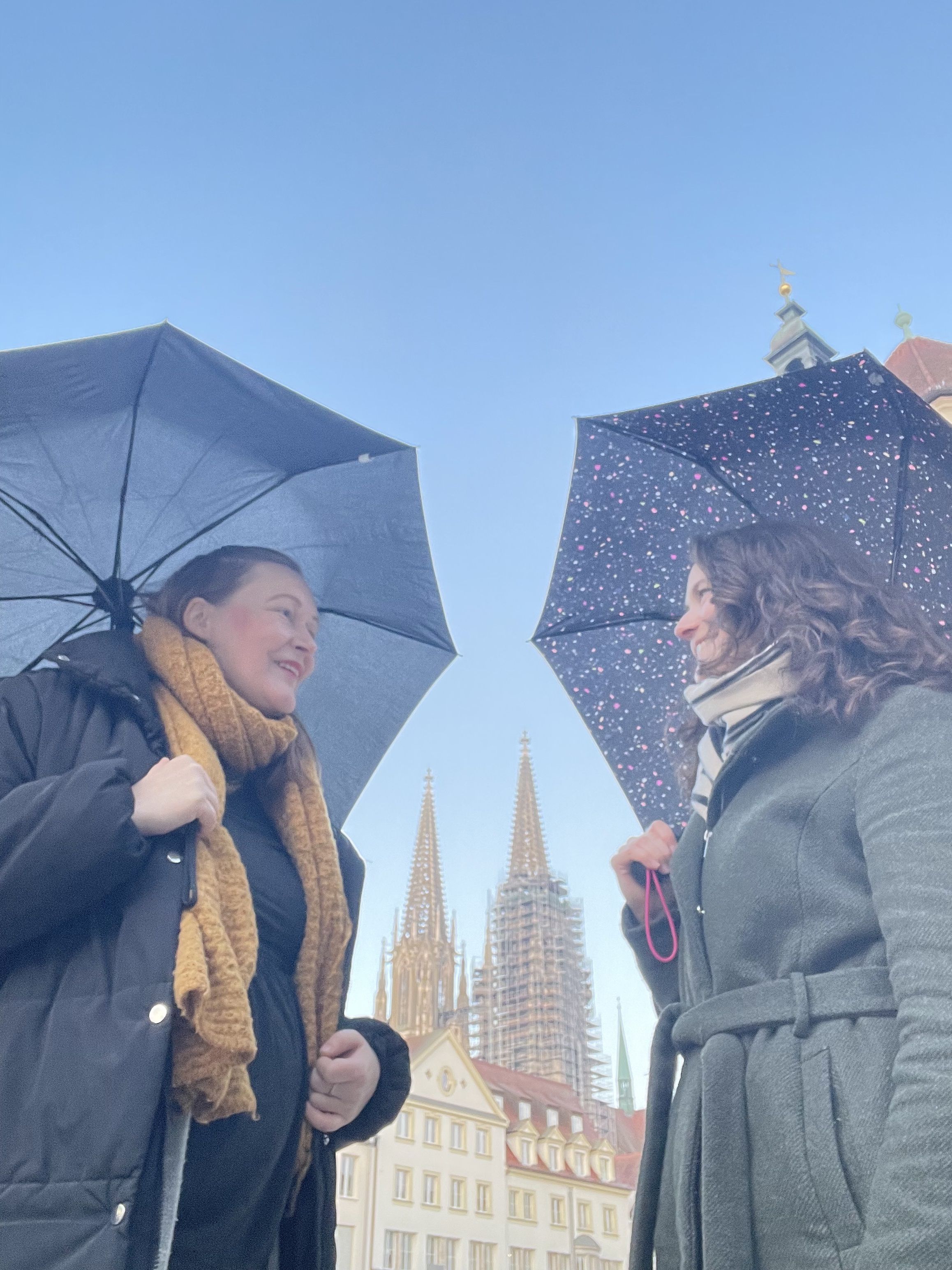 Fotografie – Projektteam (v. l.): Agnes Gerstenberg und Lisa Hörmann unter Regenschirmen, in der Mitte ist der Dom zu sehen