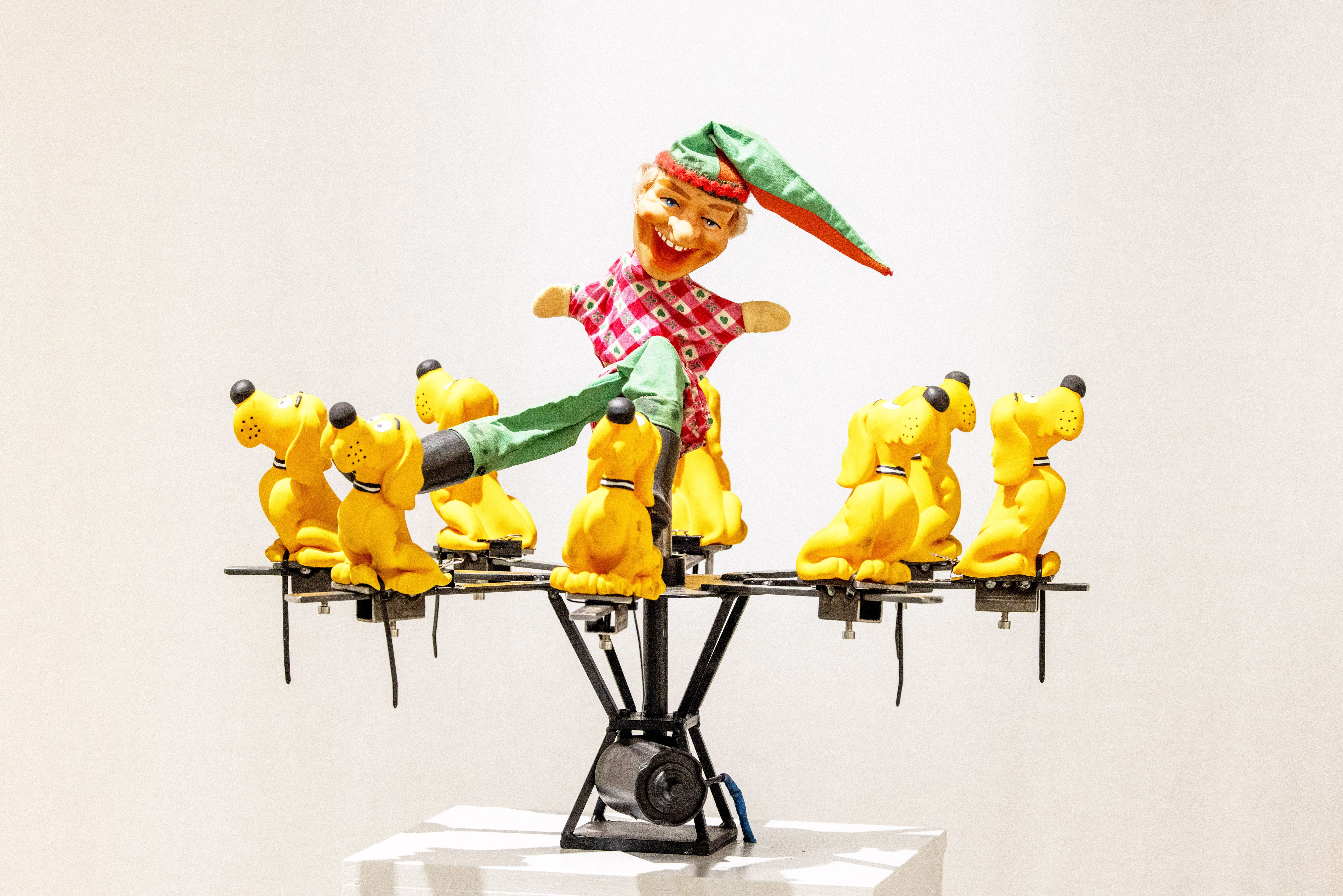 Fotografie – Kasperl-Figur umgeben von gelben Plastikhunden