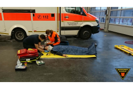 Fotografie: Teilnehmer einer Rettungssanitäter-Abschlussprüfung bei der Versorgung eines am Boden liegenden Patienten.