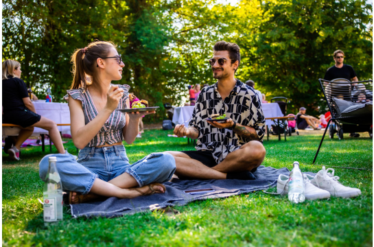 Fotografie: Ein Mann und eine Frau sitzen auf einer Picknickdecke und essen.