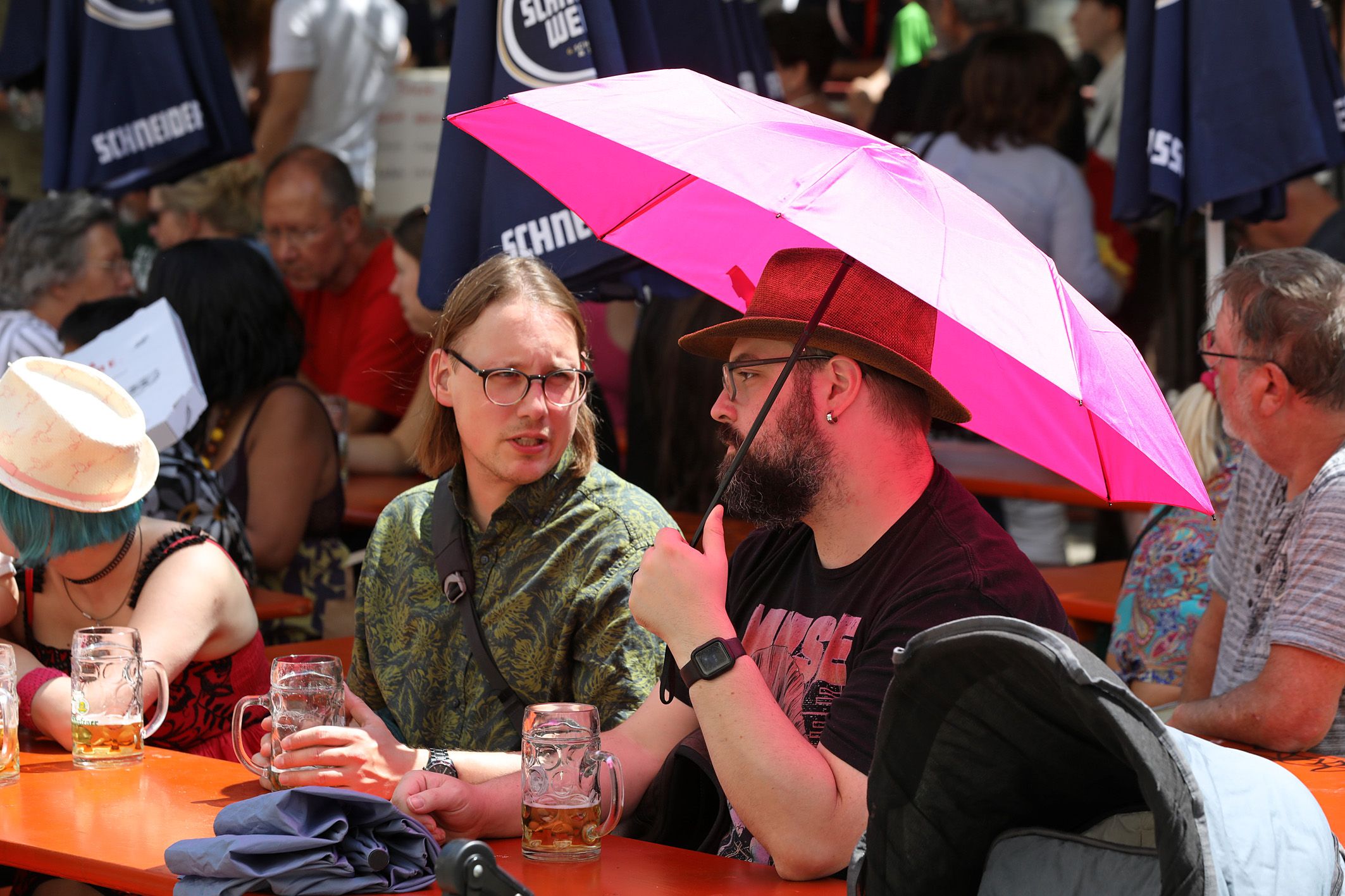 Fotografie: Menschen mit pinkem Schirm als Sonnenschutz