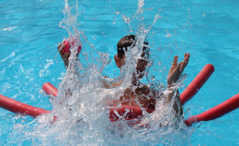Badespaß auf der Freizeitfahrt. Jugendlicher spritzt mit Wasser im Pool