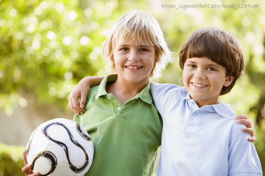 Themenbild Städtische Stiftungen - Kinder und Jugendhilfe - Symbolbild - zwei Jungs stehen Schulter an Schulter, einer hält einen Fußball in der Hand