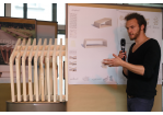 Aktion Sondermöbel - Foto einer Veranstaltung - vor einer Infowand und einem Modell eines Sitzplatzes am Mikrofon Simon Stolz (C) Bilddokumentation Stadt Regensburg