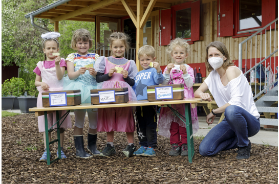 Gruppenbild. Fünf Kinder zeigen ihre Gewinne. Eine Erwachsene Frau kniet daneben.