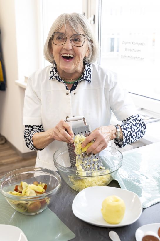 Fotografie: Eine Seniorin hobelt Äpfel.