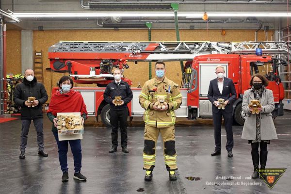 Fotografie: Bild einer Personengruppe, vor einem Drehleiterfahrzeug der Berufsfeuerwehr Regensburg.