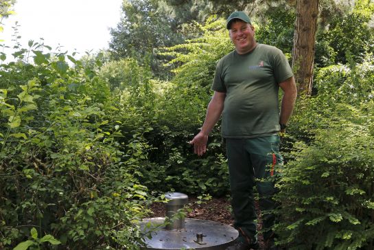 Vorarbeiter Tobias Seliger zeigt den Brunnen, aus dem Wasserlauf und Teich gespeist werden.