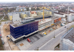 Fotografie - Rohbau der Fahrzeughalle mit Obergeschossen zwischen dem Altbau (rechts) und dem Neubau (links), im Hintergrund Richtung Süden Wohnbebauung 