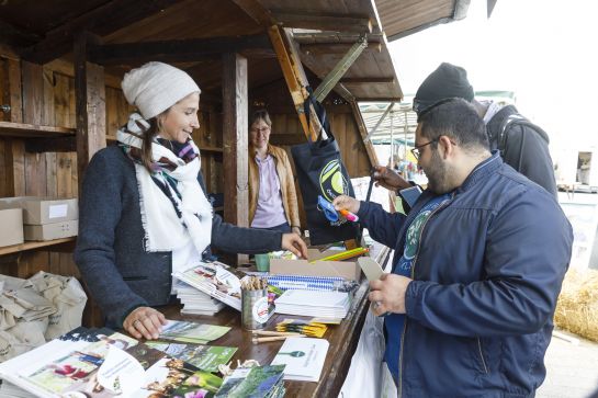 Fotografie: Elke Oelkers verteilt Werbeartikel an einem Stand am BioRegioMarkt.