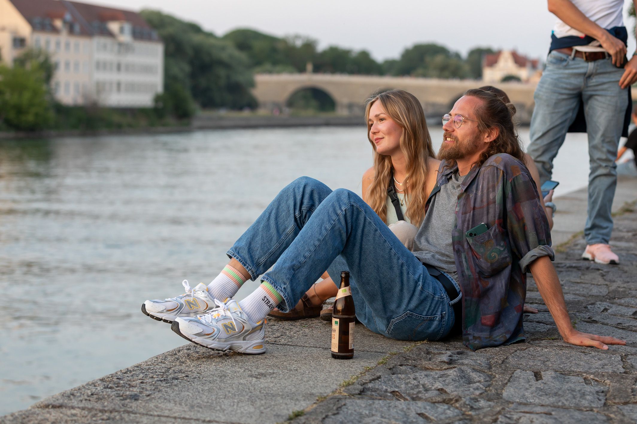 Fotografie: Eine Frau und ein Mann sitzen auf dem Weg an der Donau.