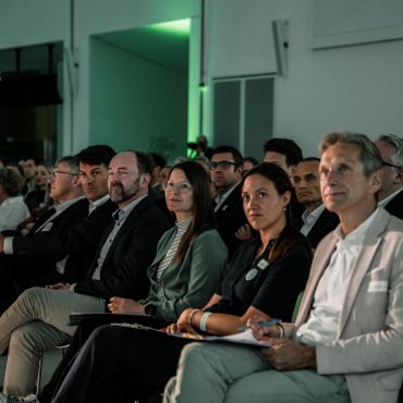 Man sieht eine Menge Personen auf Stühlen in Reihen hintereinander sitzen. Die Menschen in der vordersten Reihe haben Bewertungsbögen und Stifte vor sich liegen, da sie Teil der Jury des Zebra-Awards waren.