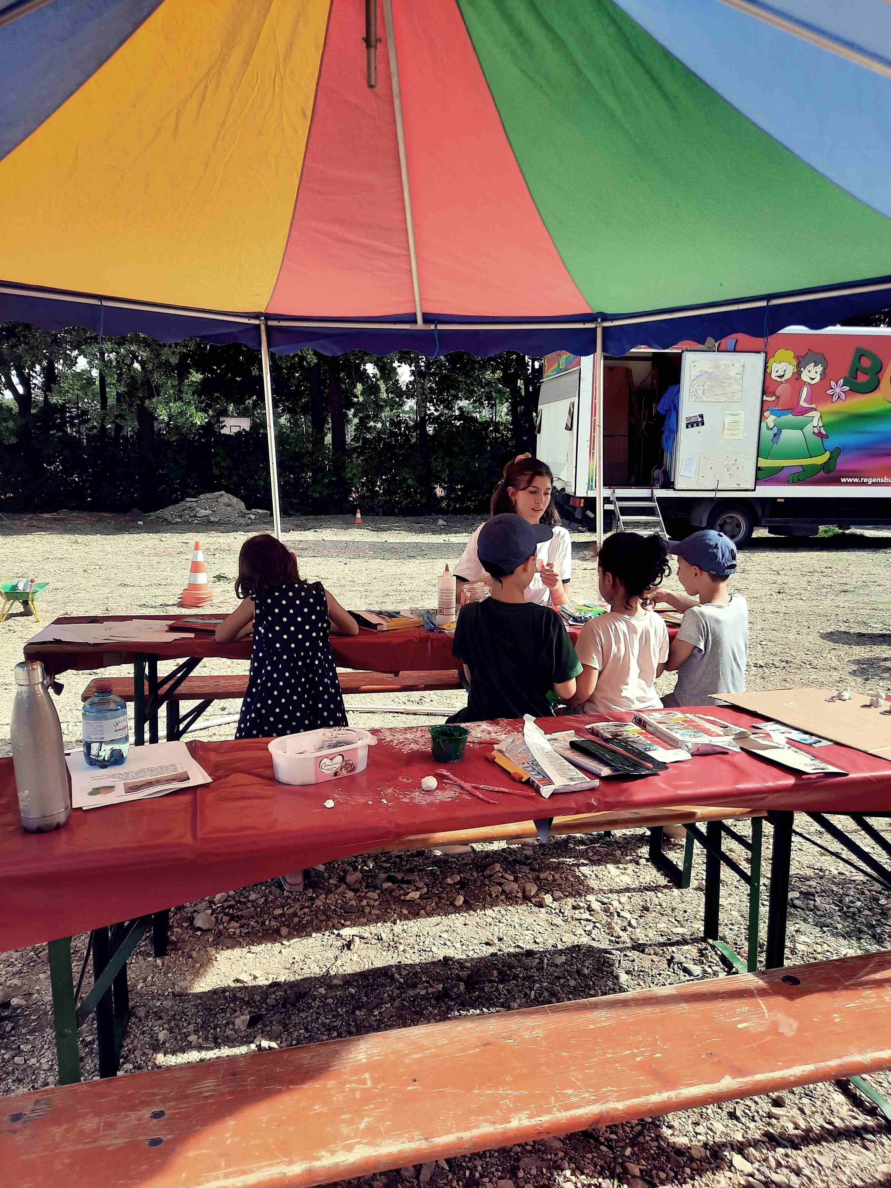 Auf dem Foto sind mehrere Kinder und eine Frau beim Basteln zu sehen.