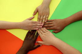 Themenbild Zuwanderung und Integration - fünf Hände unterschiedlicher Hautfarbe zeigen zueinander