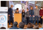 Fotografie – Dominik Bär, Geschäftsführer des Vereins Kinderfreundliche Kommunen, befragt auf der Bühne die Kinderbeiräte Bela, Dominik, Pauline, Jimi-Luke und Maximilian